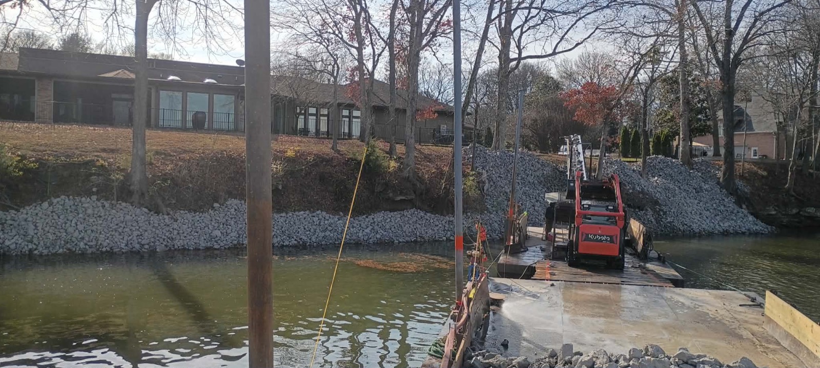 Shoreline Improvements crew placing riprap stone from their barge along a residential shoreline